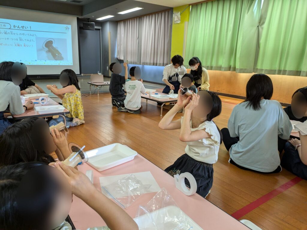 完成した工作を光にかざして中の模様を観察する子どもたち